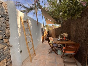 A patio area with a wooden table and chairs, a ladder, and a covered seating area. - Boutique Hostal Salinas (Sant Josep de sa Talaia)