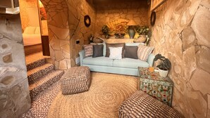 A cozy room with a stone wall, a light blue sofa, and a patterned rug. - Boutique Hostal Salinas (Sant Josep de sa Talaia)