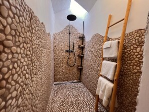 A narrow shower area with pebble-textured walls, a wooden ladder, and a towel rack. - Boutique Hostal Salinas (Sant Josep de sa Talaia)