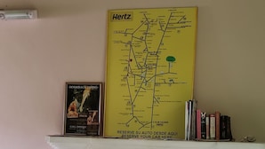 A fireplace with a yellow map above it, a framed poster, and a stack of books on the mantel.