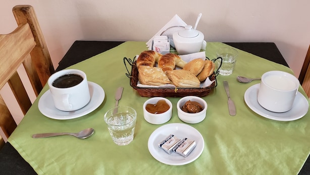 A breakfast setting with croissants, coffee, and butter on a table with a green tablecloth.