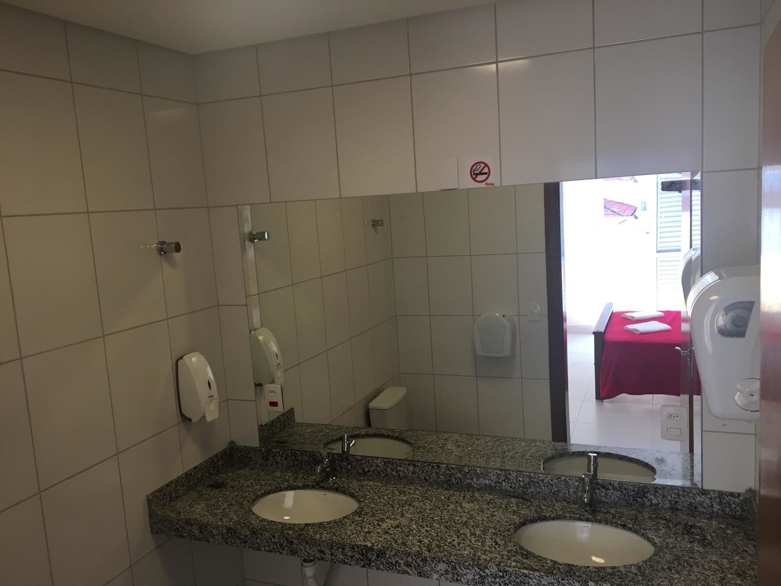 A bathroom with two sinks, a large mirror, and a red towel on a bench.