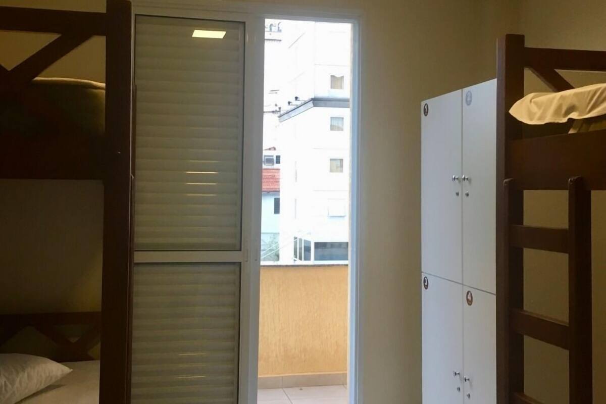 A small room with a bunk bed, a wardrobe, and a sliding door leading to a balcony.