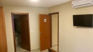 A hotel room with a bed, two towels, a TV, and an air conditioner. - Tapera Hostel (São Paulo)