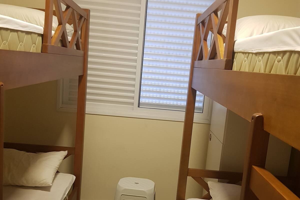 A bunk bed room with a window and a small step stool.