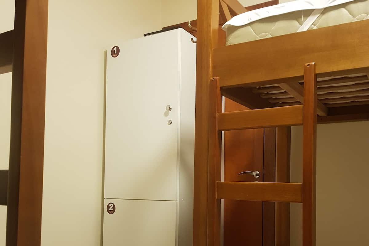 A bunk bed with a wooden ladder and a white refrigerator with two doors.