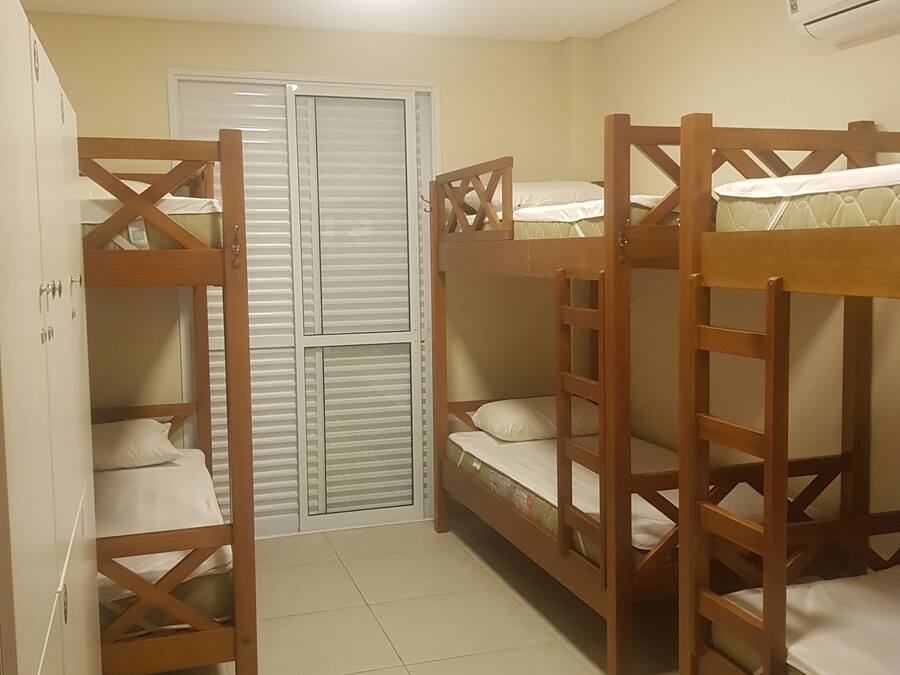 A dormitory room with bunk beds, a wardrobe, and a door with a window.