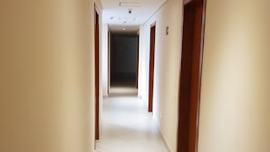 A long, narrow hallway with white tiled floors and wooden doors on both sides. - Tapera Hostel (São Paulo)