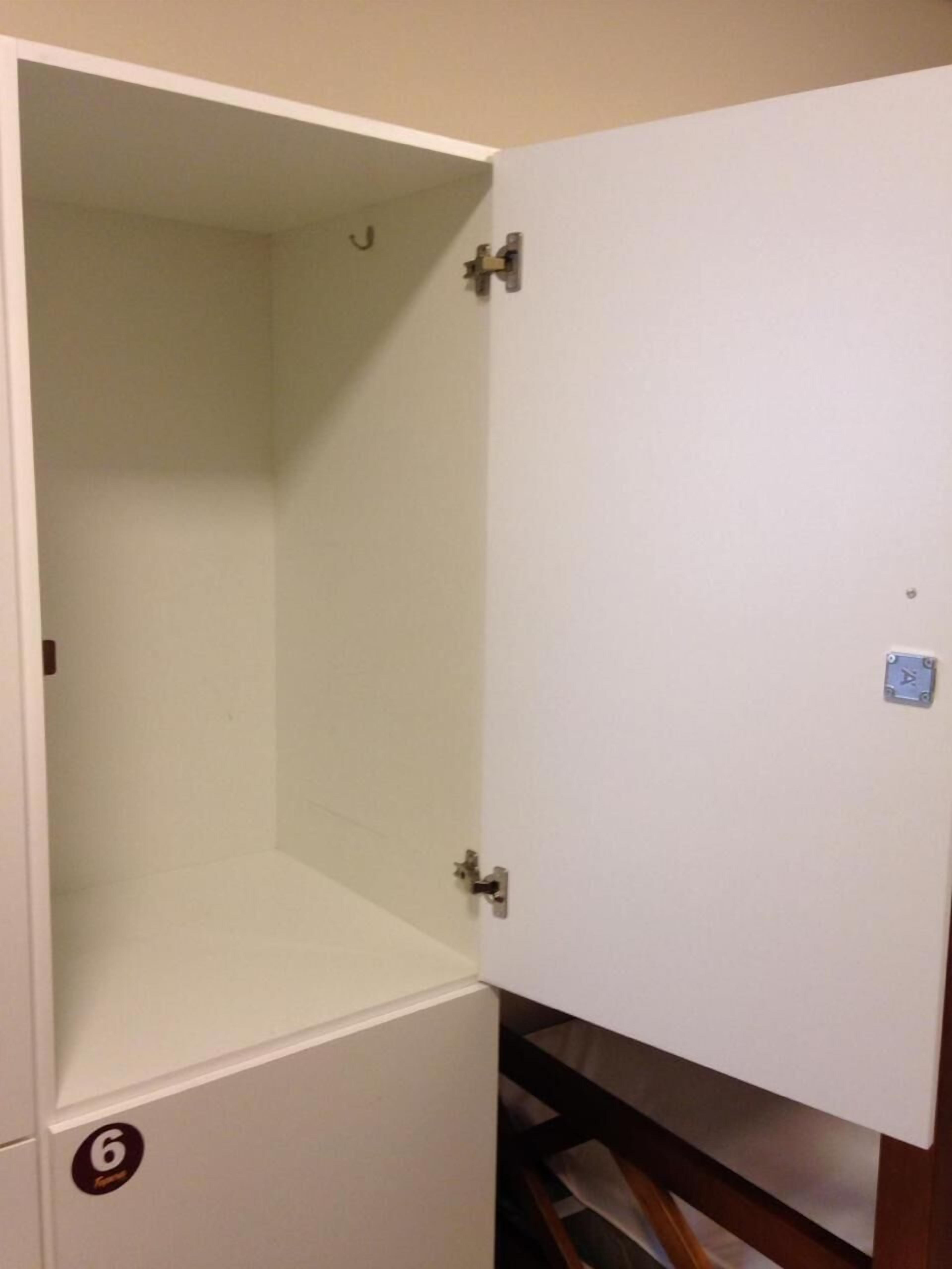 Une pièce avec une armoire blanche, une poignée de porte bien visible et un petit panneau bleu sur le mur.