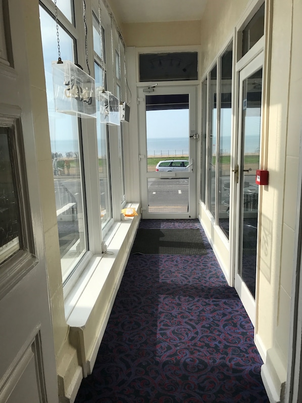 Un pasillo con alfombra estampada, ventanas amplias y vistas a la playa y al estacionamiento.