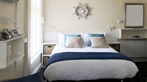 A hotel room with a bed, a ship's wheel decoration, a small table with a welcome sign, and a window. - Belmont Hotel Blackpool (Blackpool)