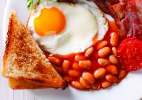 Een bord ontbijt met toast, eieren, bonen en tomaten.