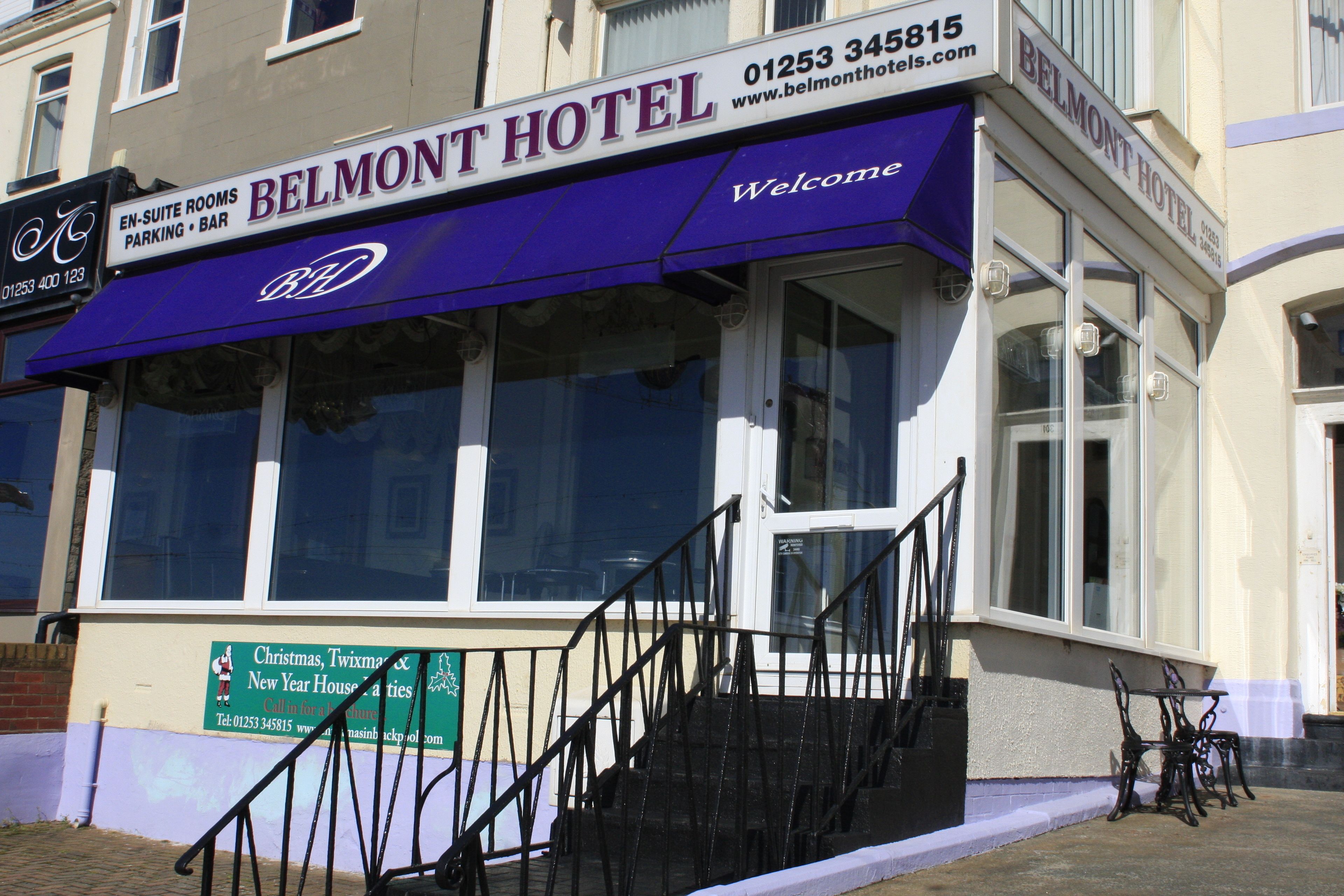 A hotel with a prominent sign reading "BELMONT HOTEL" and a website address.