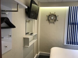 Een hotelkamer met een bed, een wandtelevisie, een decoratieve scheepshoeveel en een raam met zonwering.