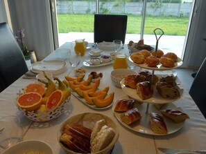 A breakfast table with various food items, including fruits, pastries, and beverages. - Maison de Luciné (Combourg)