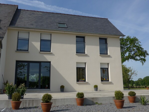 A two-story building with a flat roof, large windows, and potted plants in front. - Maison de Luciné (Combourg)