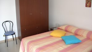 Een slaapkamer met een bed, een kledingkast, een stoel en een decoratie aan de muur.