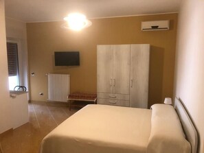 A bedroom with a bed, a wardrobe, a radiator, a television, and a window with blinds. - B&B Il Sogno (Montescaglioso)