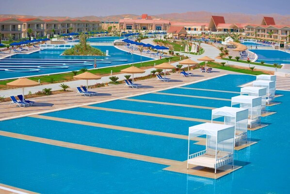 A large outdoor swimming pool with multiple lanes, surrounded by lounge chairs and umbrellas. - Pickalbatros Sea World Resort - Marsa Alam- "Aqua Park" - All inclusive (El Quseir)
