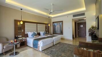 A modern hotel room with a large bed, a desk, a chair, and a ceiling fan.