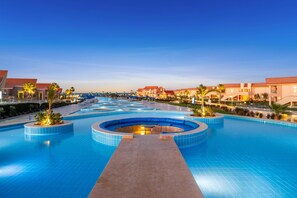 A large, circular pool with a central walkway, surrounded by palm trees and hotel buildings. - Pickalbatros Sea World Resort - Marsa Alam- "Aqua Park" - All inclusive (El Quseir)