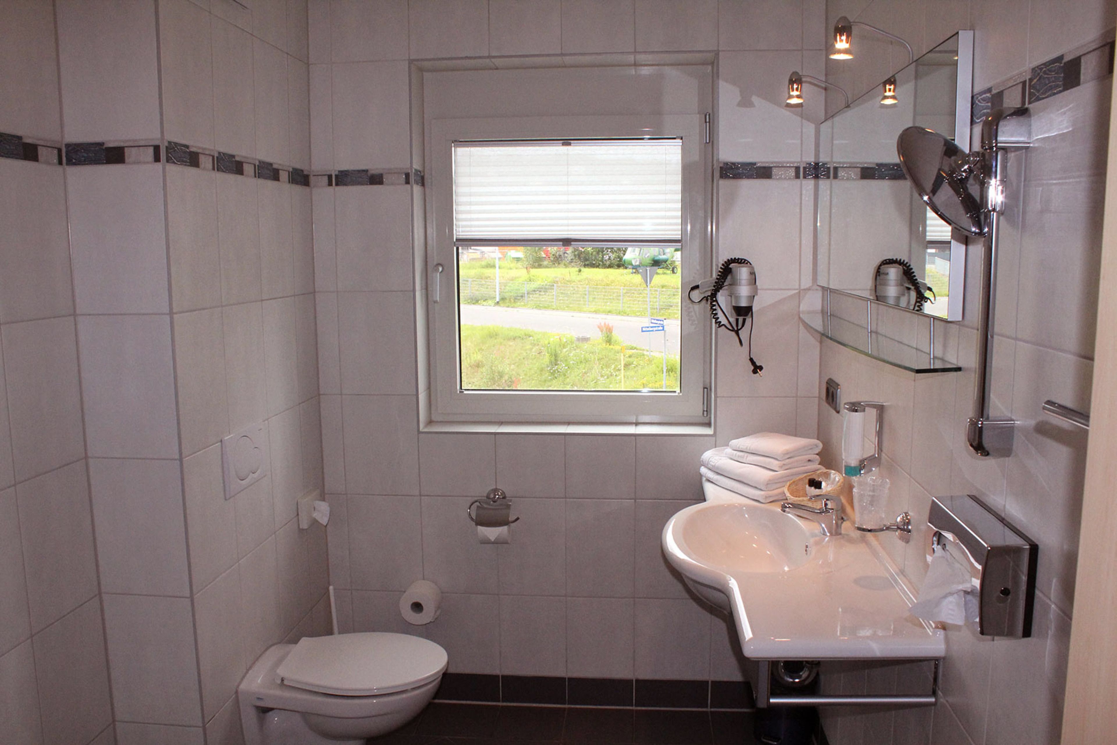 Ein Badezimmer mit Toilette, Waschbecken und Fenster.