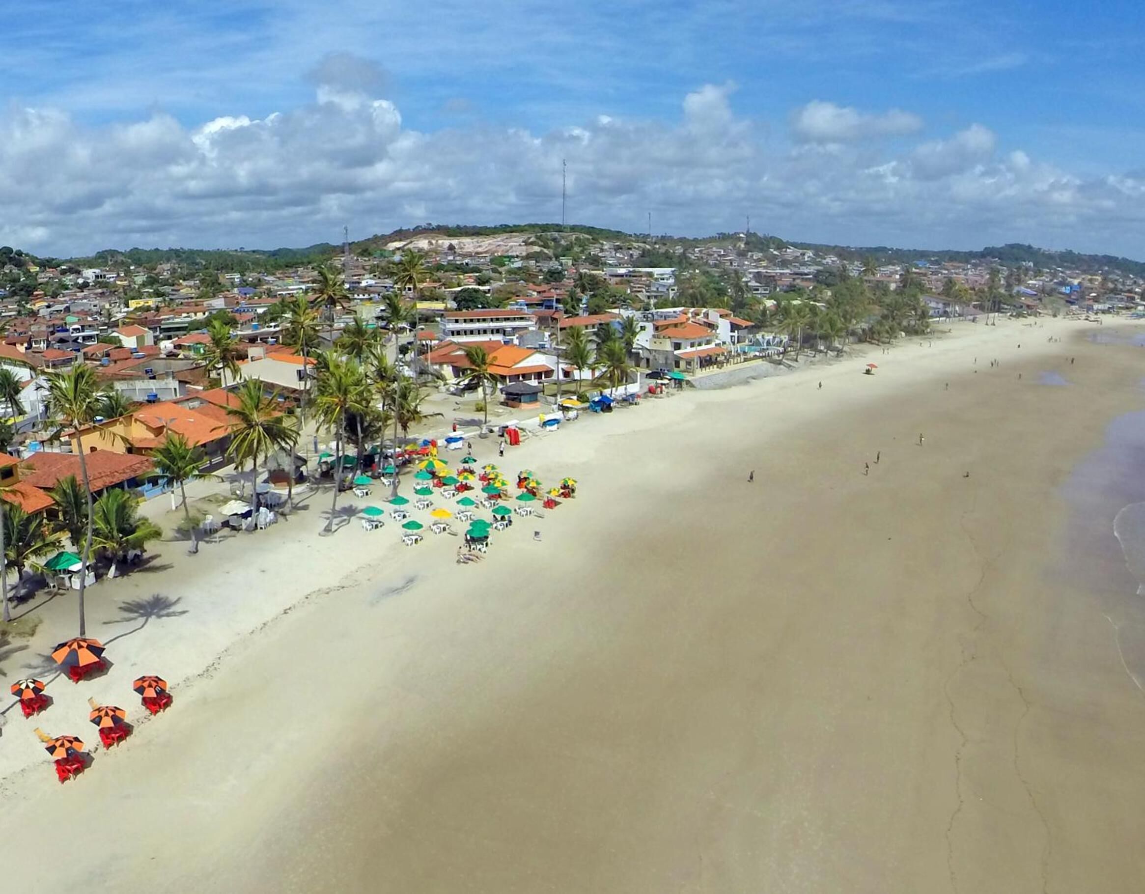 Ein Strand mit einer Reihe von Häusern und Palmen.