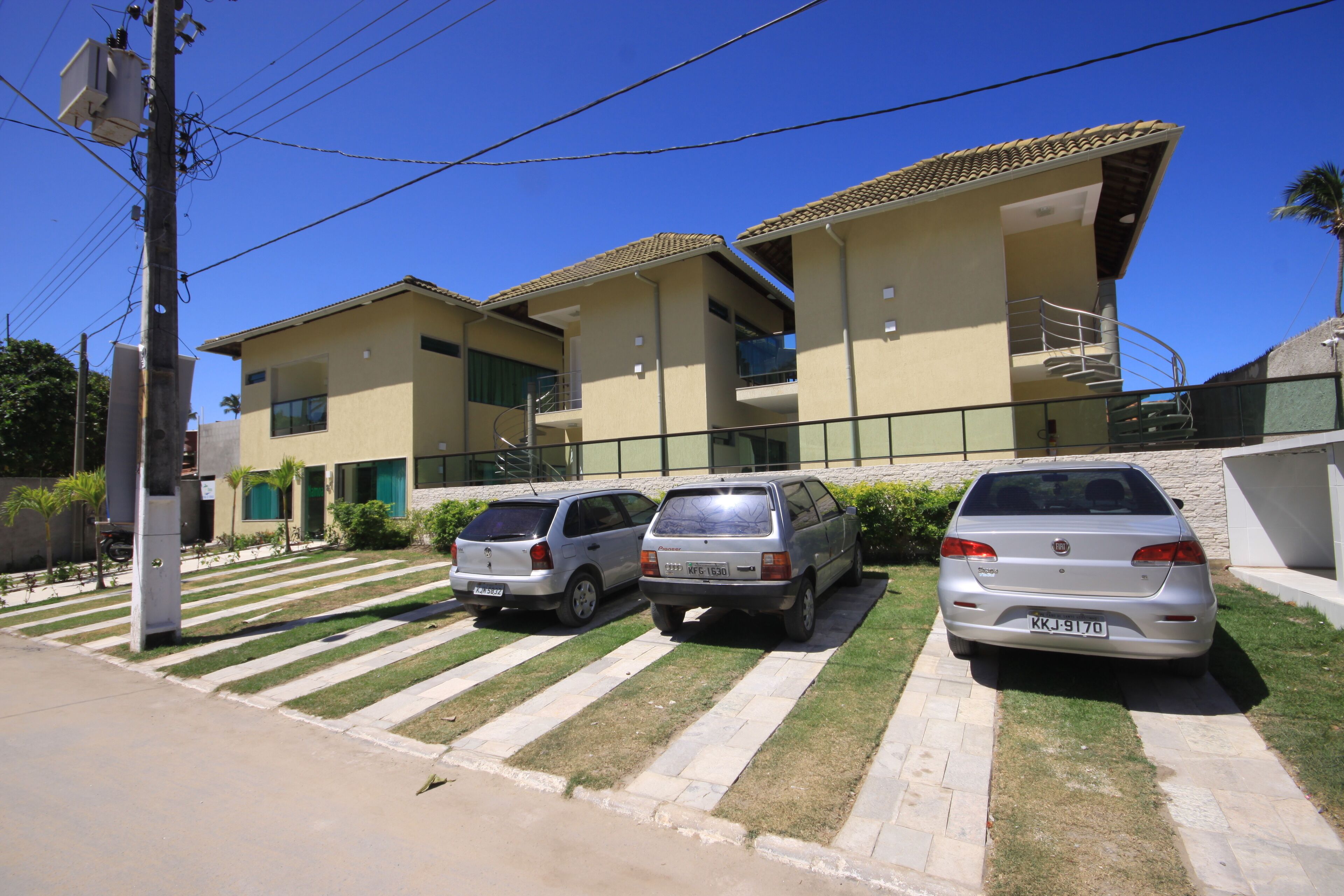 Un edifici residencial amb teulada de rajola, una escala i dos cotxes aparcats.