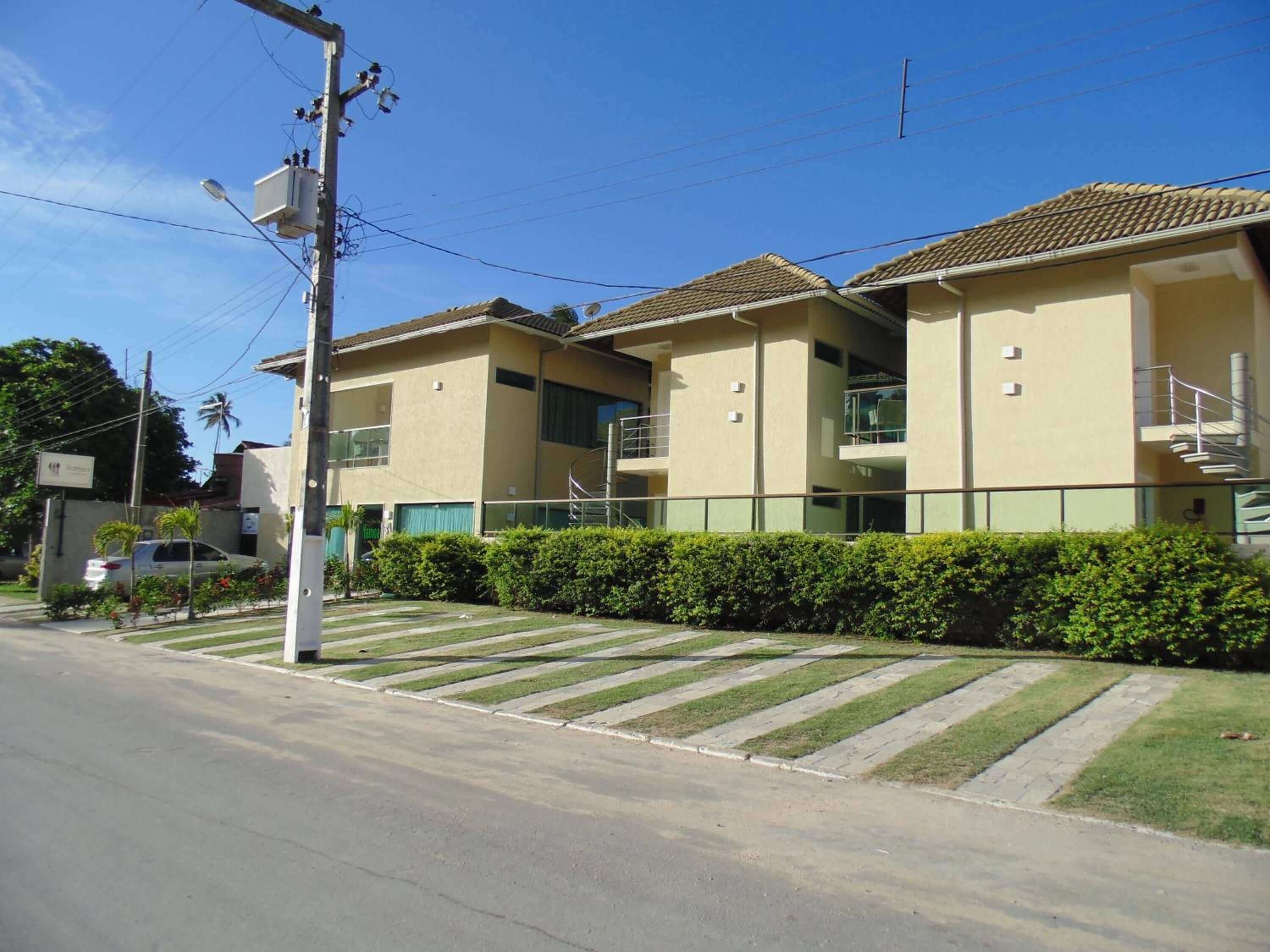 A two-story building with a flat roof, a staircase on the right side, and a parking area in front.