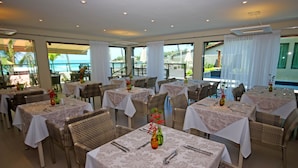 A restaurant with multiple tables, wicker chairs, and white tablecloths. - Namoa Pousada (Cabo de Santo Agostinho)