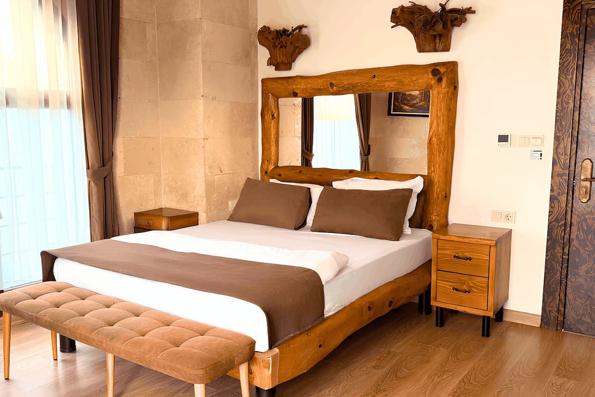A bedroom with a wooden bed, a bench, a nightstand, a dresser, and a door.