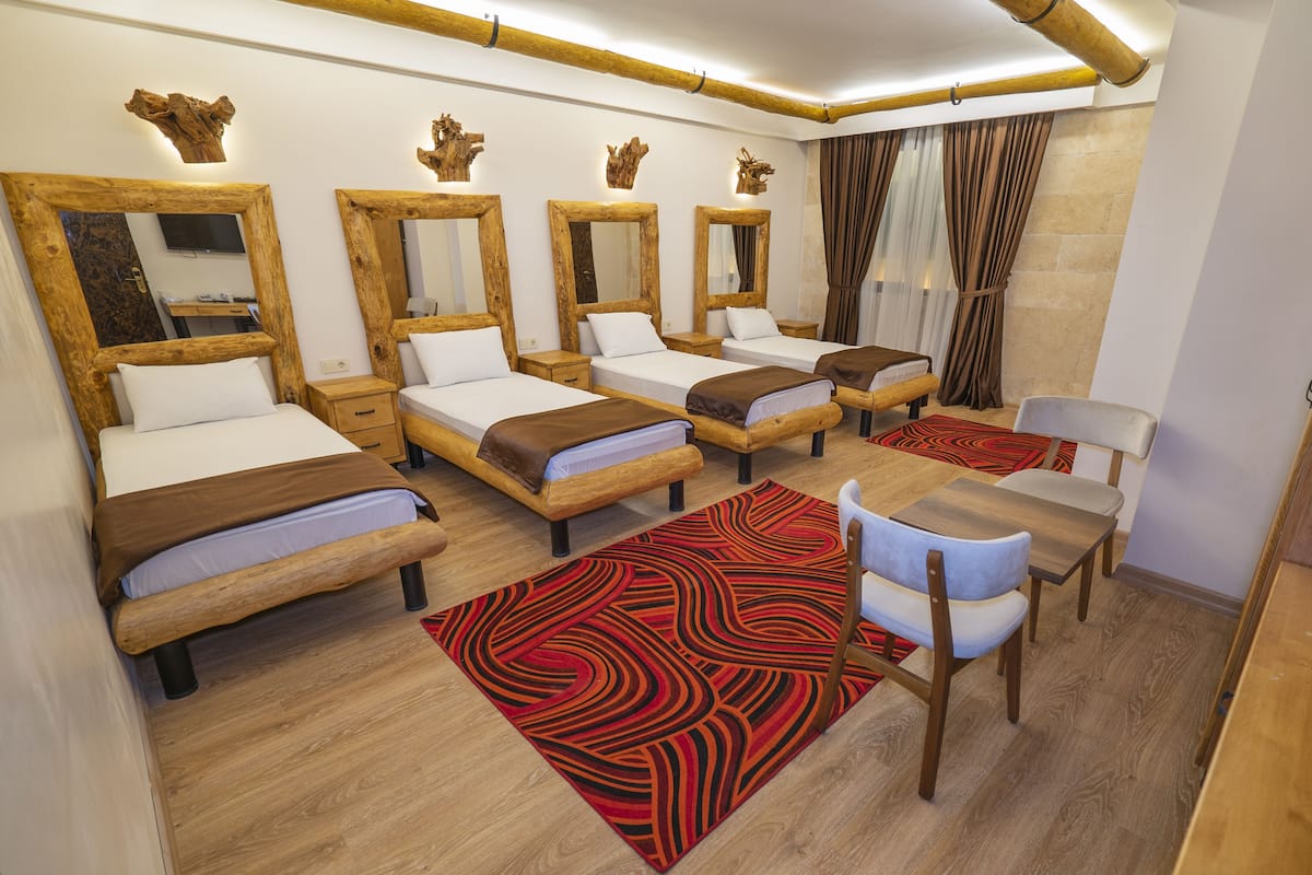 A hotel room with four beds, a dining table, and chairs.