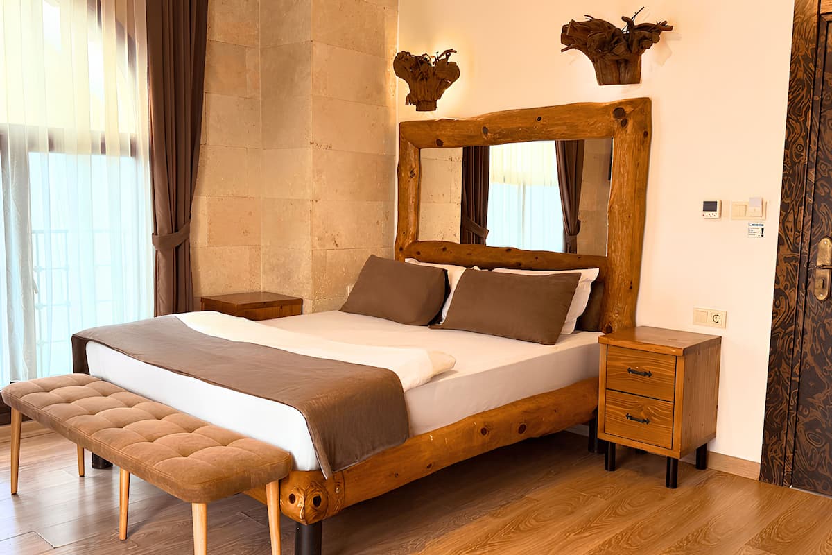 A wooden bed with a large mirror, a bench, and a nightstand with drawers.