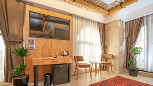 A compact living space with a kitchenette, a flat-screen TV, a dining area, and two potted plants. - Pasha Palace Hotel (Istanbul)