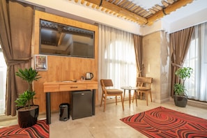 A compact living space with a kitchenette, a flat-screen TV, a dining area, and two potted plants. - Pasha Palace Hotel (Istanbul)