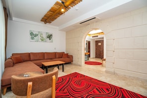A modern living room with a sectional sofa, a wooden coffee table, and a red patterned rug. - Pasha Palace Hotel (Istanbul)