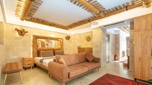 A modern bedroom with a wooden ceiling, a large bed, a sofa, and a red patterned rug. - Pasha Palace Hotel (Istanbul)
