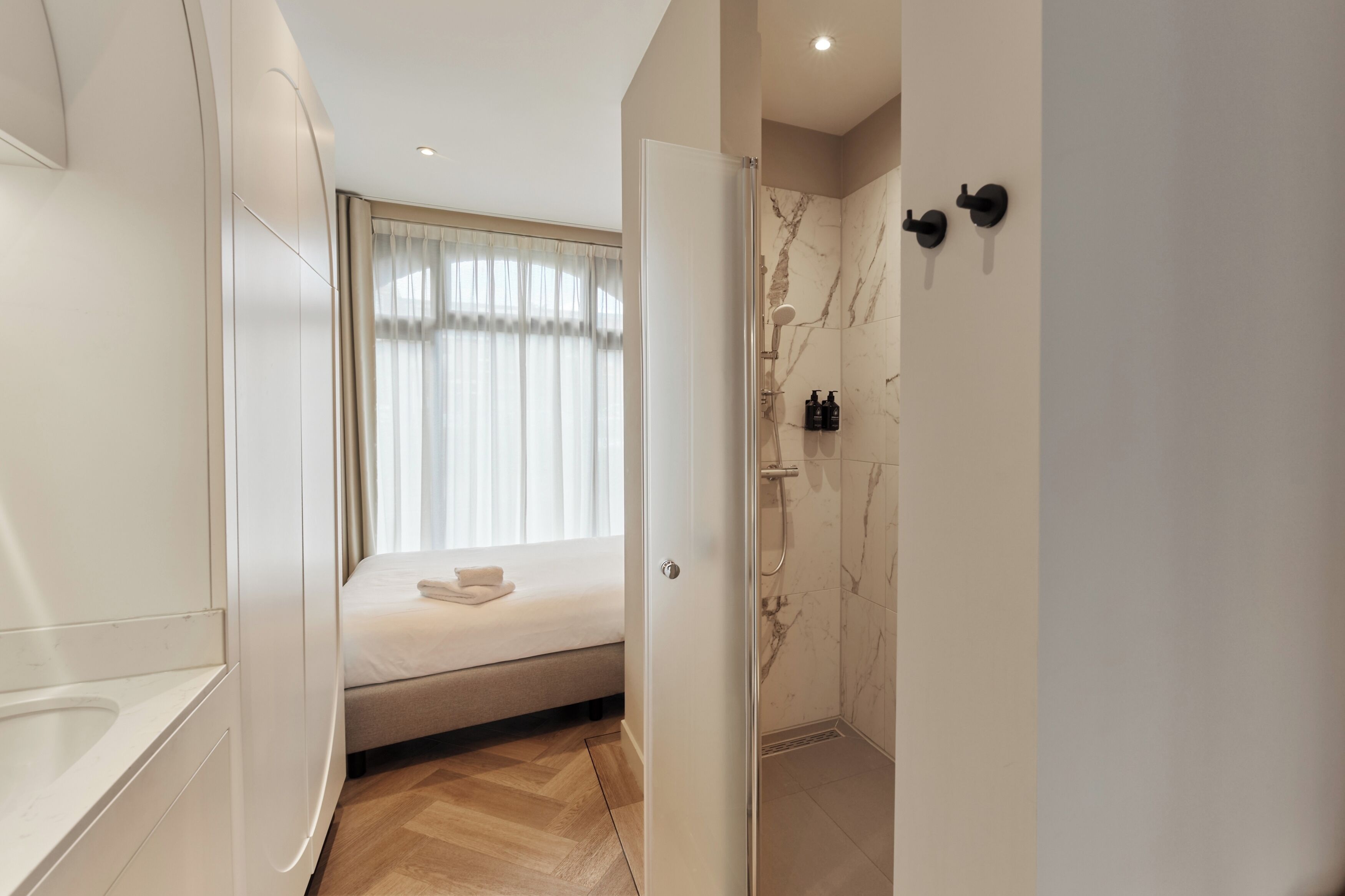 A modern bathroom with a shower, a toilet, and a bed with a window.
