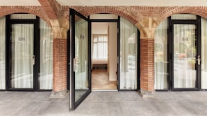 A hotel entrance with glass doors, brick arches, and numbered room doors. - The Anthony Hotel (Utrecht)