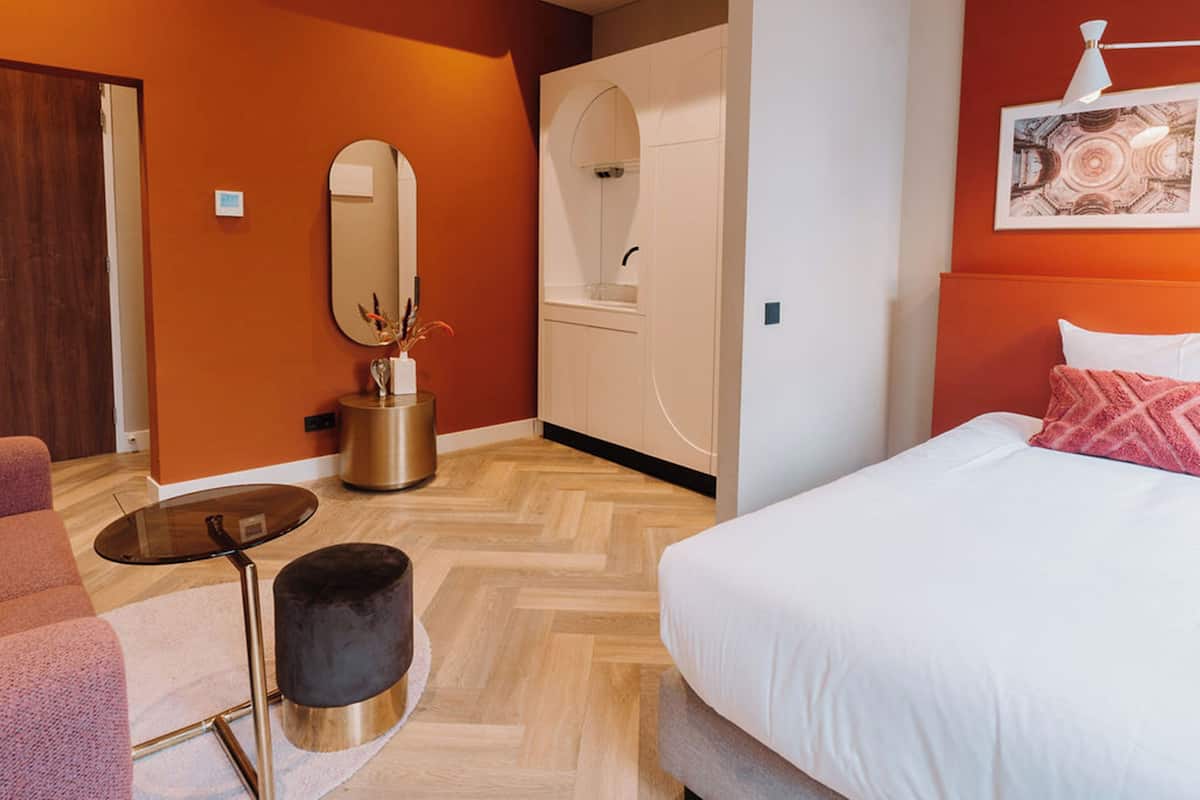 A modern bedroom with a bed, a round mirror, a small round table, and a wardrobe.