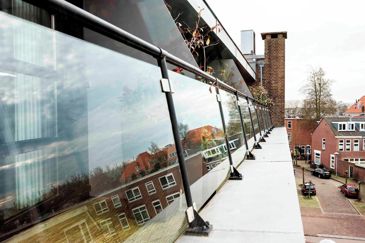 A modern building with large reflective glass windows and a brick chimney.
