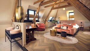 A loft-style bedroom with exposed wooden beams, a round table, a sofa, and a bed. - The Anthony Hotel (Utrecht)