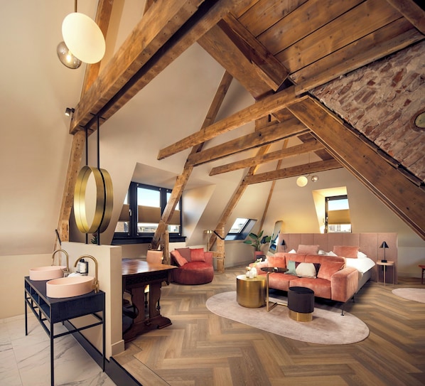 Un dormitorio estilo loft con vigas de madera a la vista, una mesa redonda, un sofá y una cama.