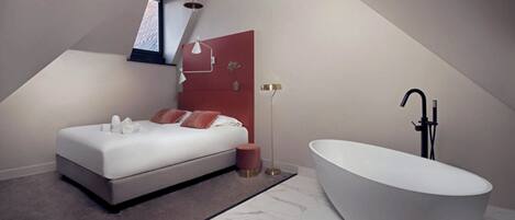 A modern bedroom with a large bed, a freestanding bathtub, and a skylight.