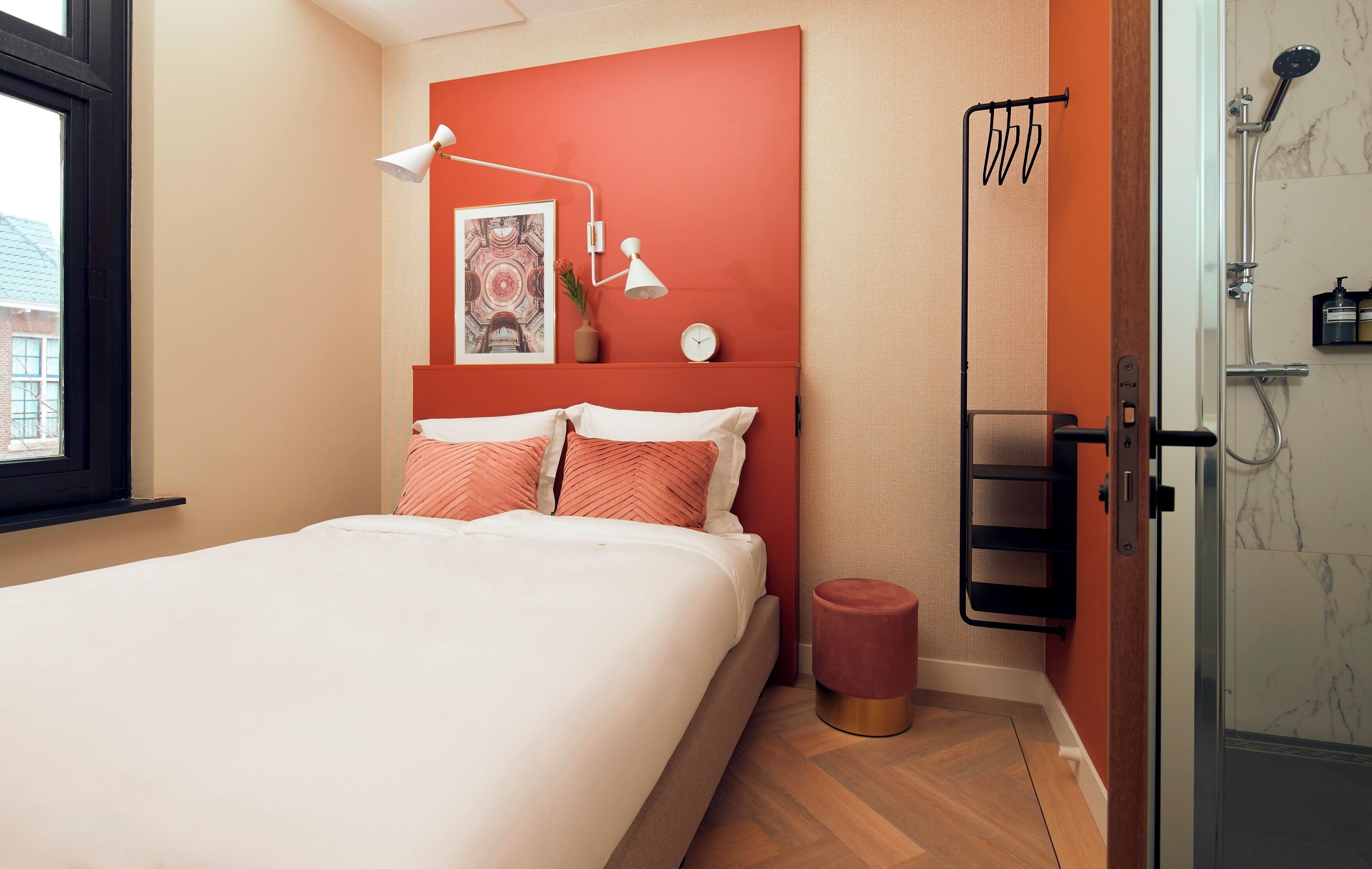 A modern bedroom with a bed, a bedside lamp, a clock, and a shower area.