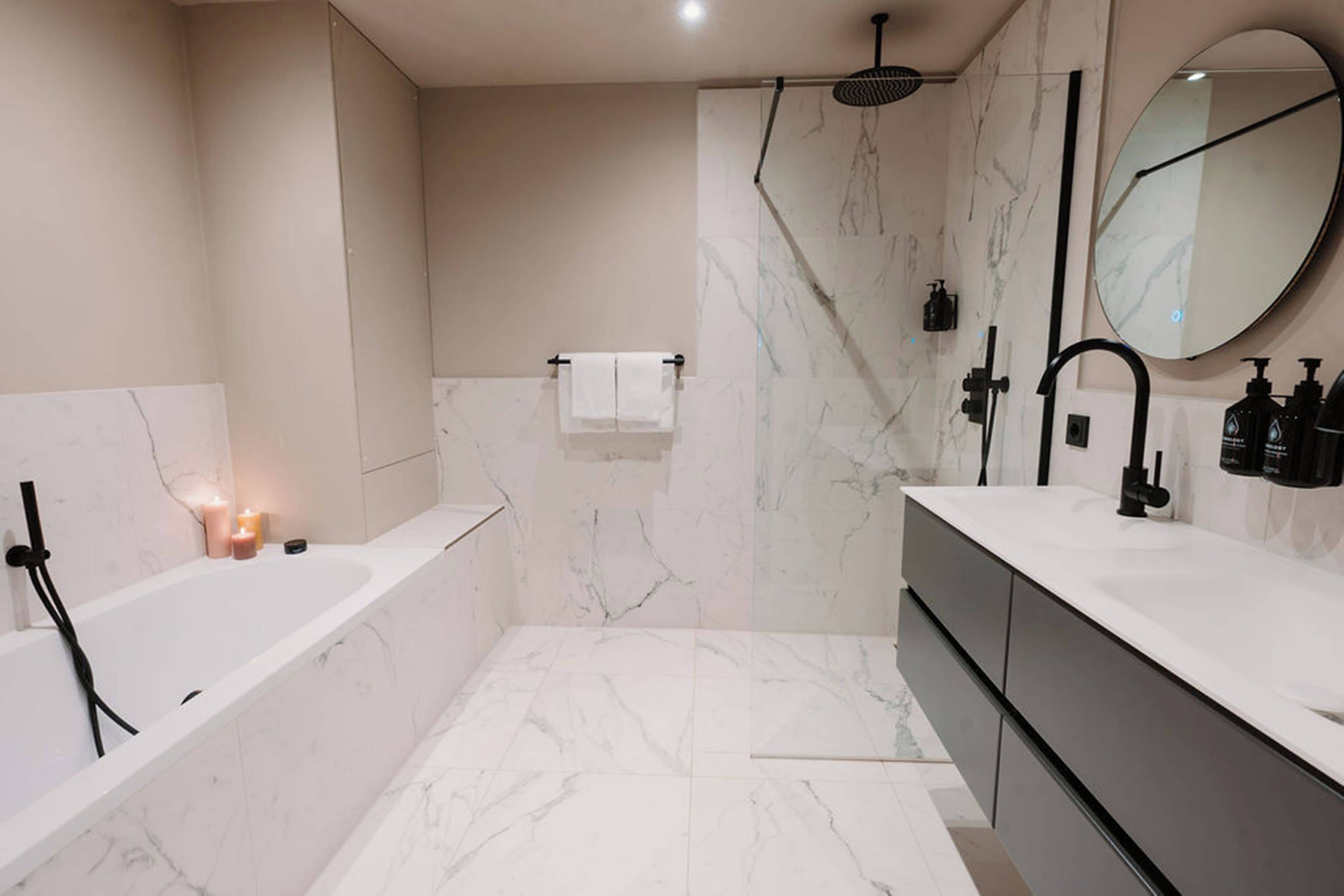 A modern bathroom with a bathtub, shower, and vanity.