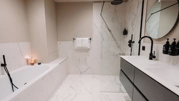 A modern bathroom with a bathtub, shower, and vanity.