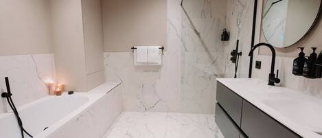 A modern bathroom with a bathtub, shower, and vanity.