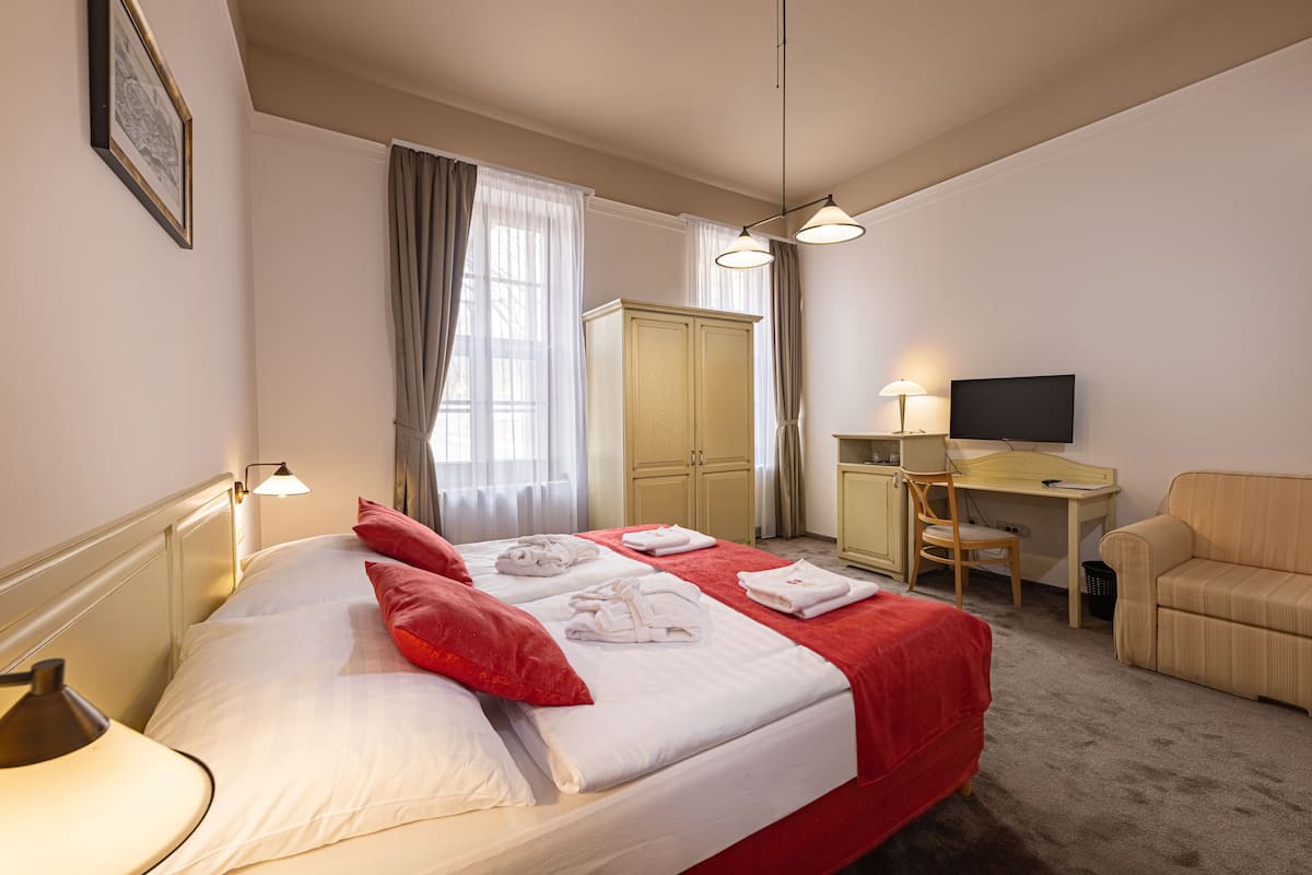 Une chambre d’hôtel équipée d’un lit, d’un bureau, d’une chaise et d’un téléviseur.