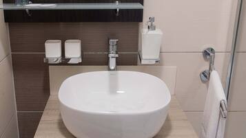 A modern bathroom with a large white sink, a mirror above it, and a towel rack to the right.